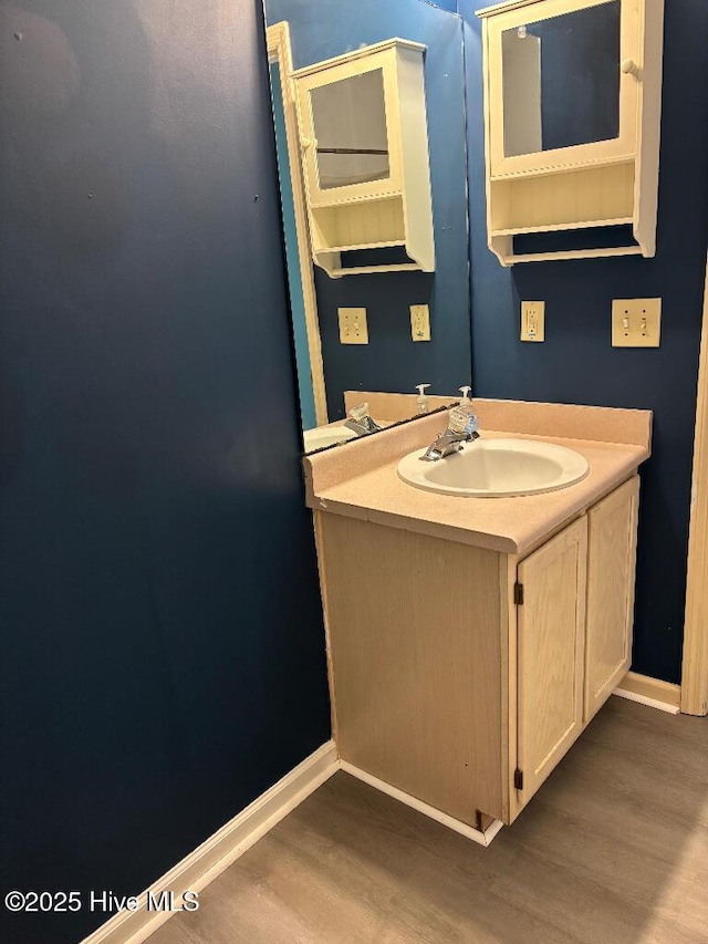 bathroom with wood finished floors, baseboards, and vanity