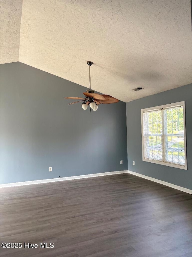 spare room with a textured ceiling, a ceiling fan, dark wood-style floors, baseboards, and vaulted ceiling