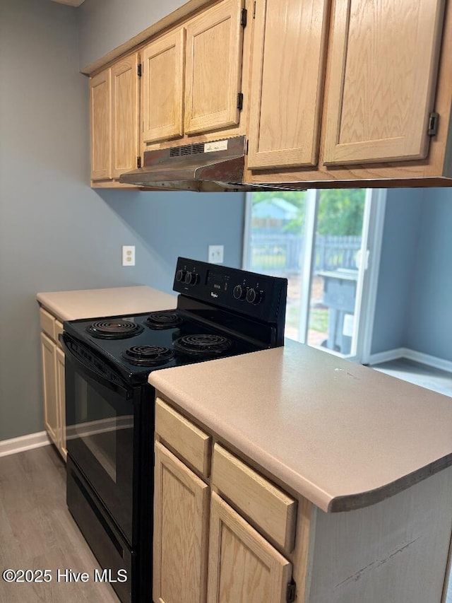 kitchen featuring black range with electric cooktop, under cabinet range hood, light wood-style flooring, and light countertops