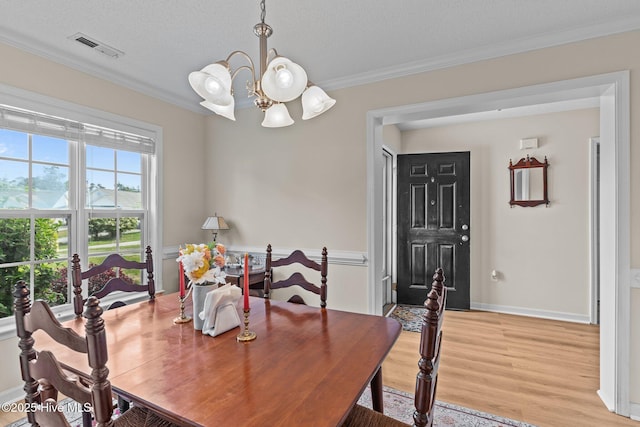 4979 Montserrat Dr, Southport, NC 28461 - dining area featuring a chandelier, light wood finished floors, crown molding, a textured ceiling, and baseboards