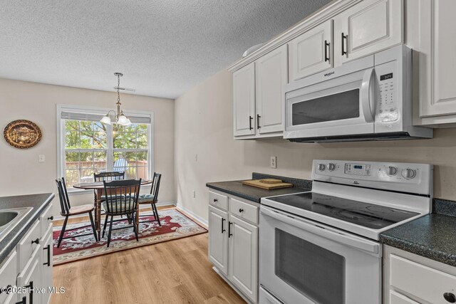 4979 Montserrat Dr, Southport, NC 28461 - kitchen with white appliances, dark countertops, light wood-style floors, white cabinetry, and a textured ceiling
