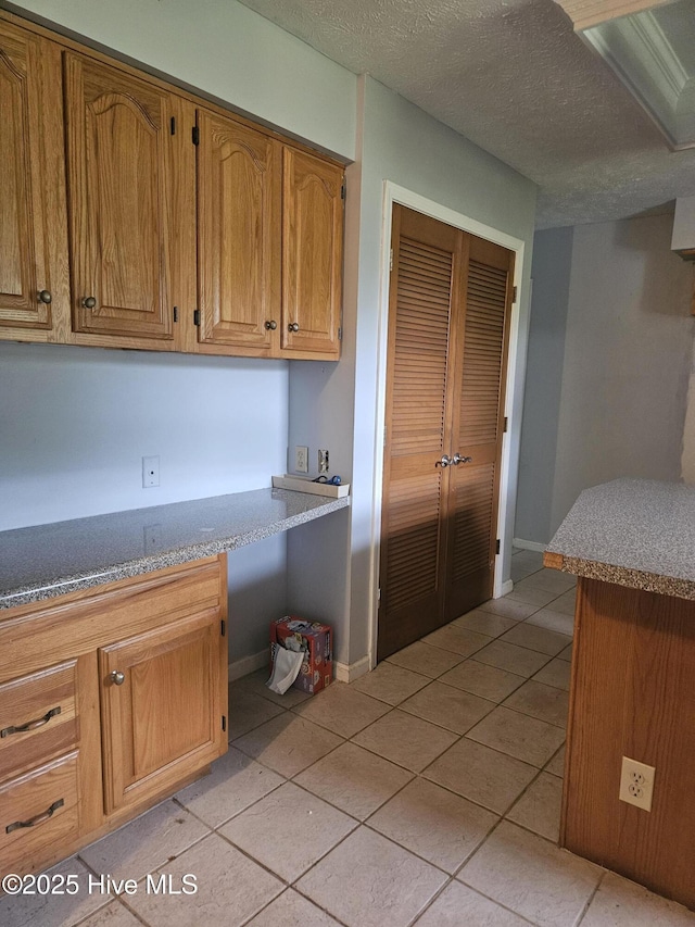 4 Cleek Ct, Carolina Shores, NC 28467 - kitchen featuring light tile patterned flooring, brown cabinetry, baseboards, and a textured ceiling