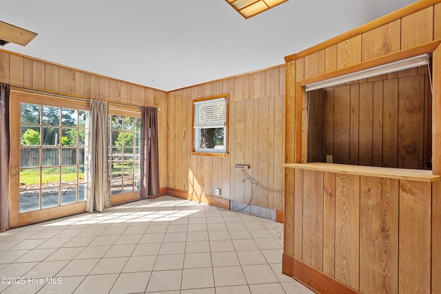 spare room with wood walls, baseboards, and light tile patterned flooring