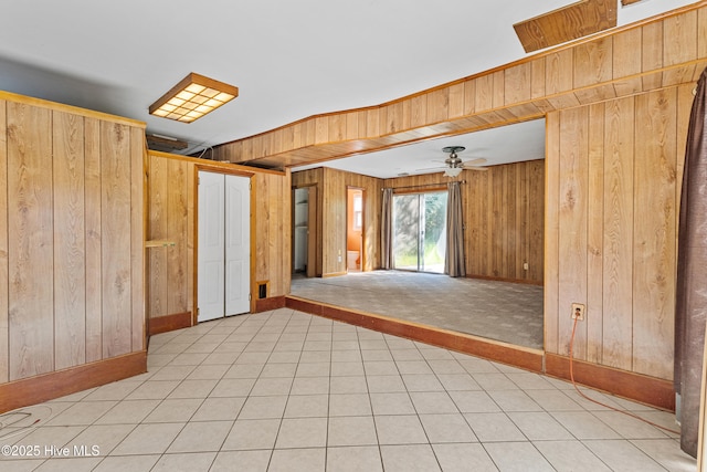 spare room with wood walls, a ceiling fan, and baseboards