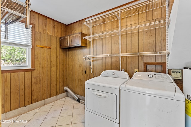 washroom featuring washer and clothes dryer, wooden walls, light tile patterned floors, and water heater
