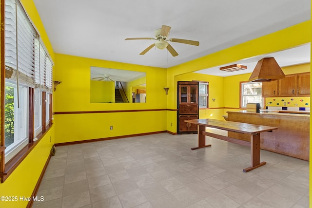 kitchen featuring a ceiling fan, baseboards, brown cabinetry, and freestanding refrigerator