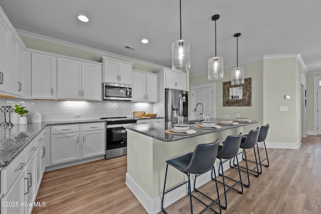 357 Spicer Lake Dr, Holly Ridge, NC 28445 - kitchen with stainless steel appliances, crown molding, white cabinetry, a breakfast bar area, and light wood finished floors