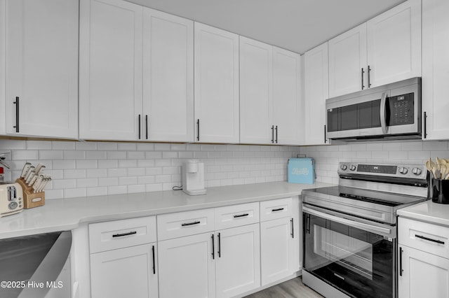 kitchen featuring stainless steel appliances, white cabinetry, light countertops, and backsplash