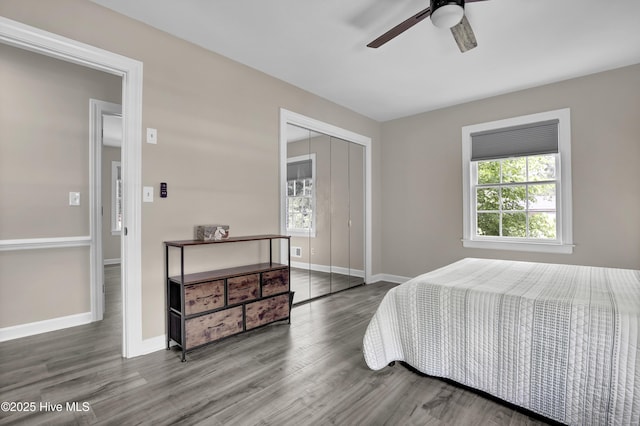 bedroom with a closet, wood finished floors, baseboards, and a ceiling fan