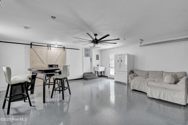 living area with a barn door and a ceiling fan