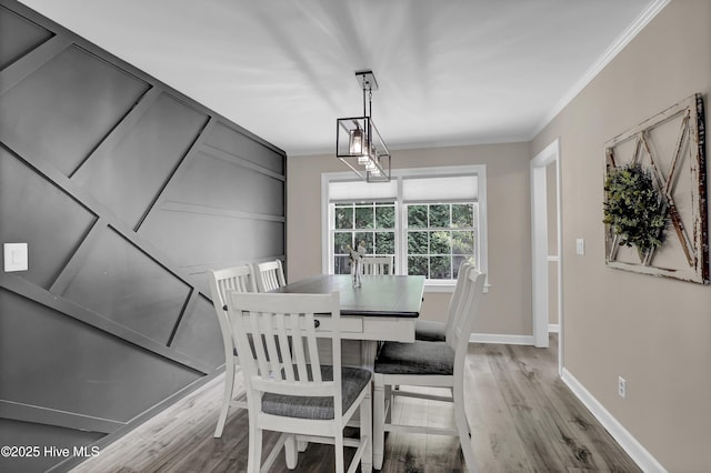 dining room with wood finished floors, ornamental molding, and baseboards
