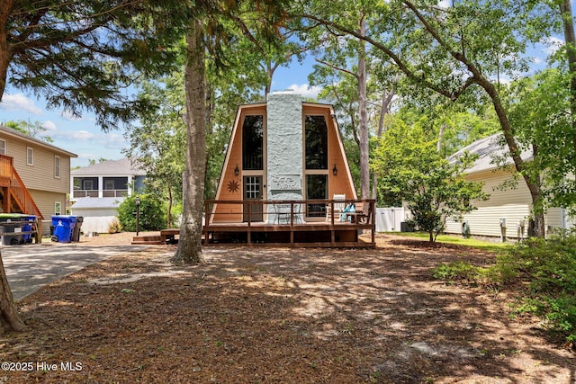 159 NE 31st St, Oak Island, NC 28465 - rear view of house with a wooden deck and a chimney