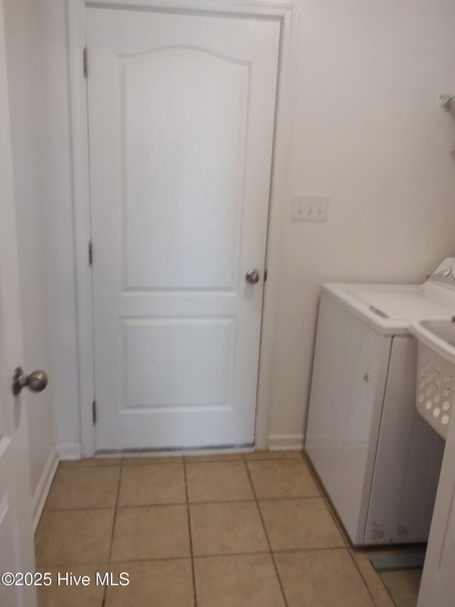 clothes washing area with light tile patterned floors, separate washer and dryer, and baseboards