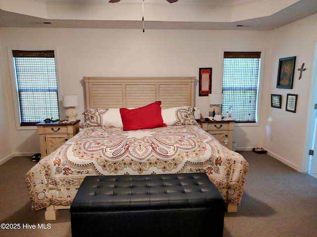 carpeted bedroom featuring baseboards, a raised ceiling, crown molding, and a ceiling fan