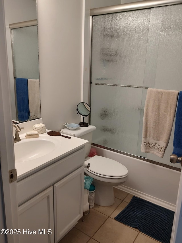 bathroom featuring tile patterned flooring, vanity, enclosed tub / shower combo, and toilet