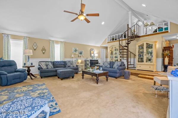 carpeted living area featuring high vaulted ceiling, a ceiling fan, and stairs