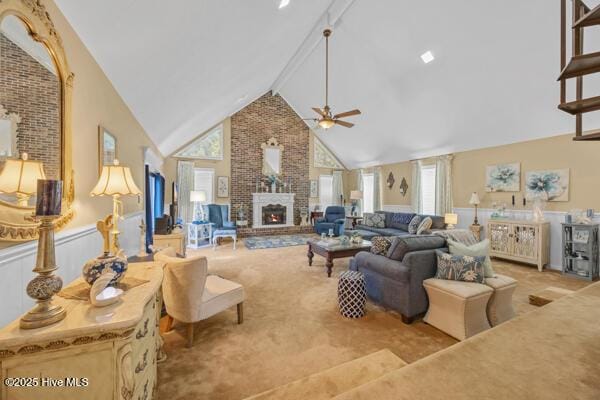 carpeted living room with a ceiling fan, a brick fireplace, high vaulted ceiling, and beam ceiling