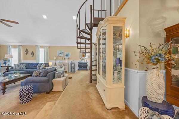 living room with carpet floors, ceiling fan, and stairway