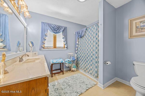 full bath with toilet, vanity, a shower with curtain, and baseboards
