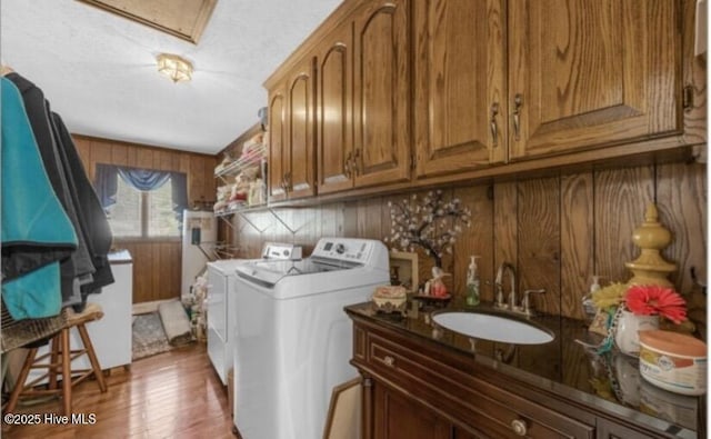 laundry room featuring separate washer and dryer, wood walls, and light wood-style floors