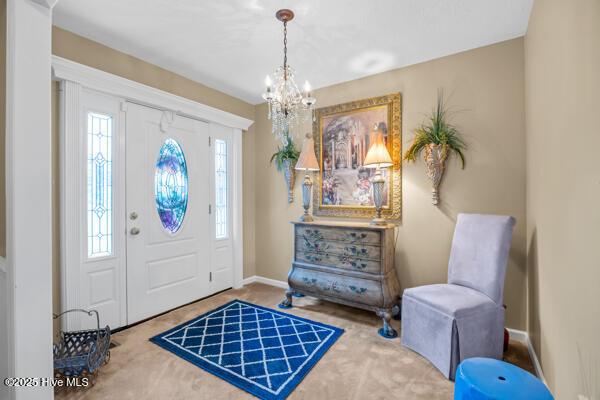 foyer entrance with a chandelier and baseboards