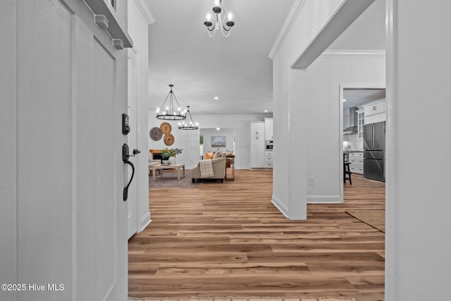 foyer entrance featuring a chandelier, ornamental molding, wood finished floors, baseboards, and recessed lighting