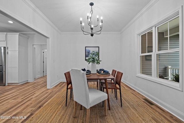 dining room with a chandelier, light wood finished floors, ornamental molding, and baseboards
