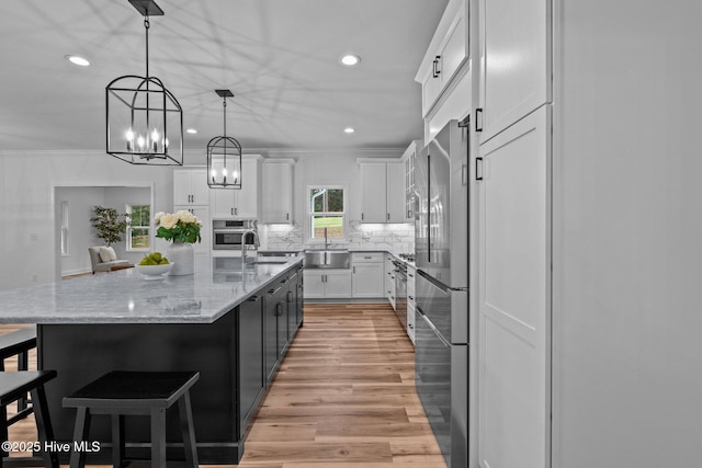 kitchen with recessed lighting, white cabinets, appliances with stainless steel finishes, tasteful backsplash, and a kitchen bar