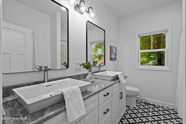 full bathroom with tile patterned floors, toilet, double vanity, and baseboards