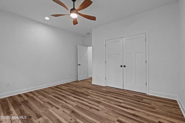 unfurnished bedroom featuring wood finished floors, baseboards, a closet, recessed lighting, and a ceiling fan