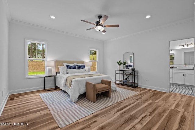 bedroom featuring light wood-type flooring, crown molding, multiple windows, baseboards, and a sink