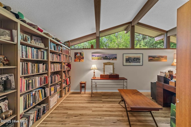 living area featuring baseboards, wood finished floors, a textured ceiling, and bookshelves