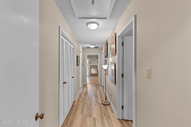 hallway with light wood-type flooring and baseboards