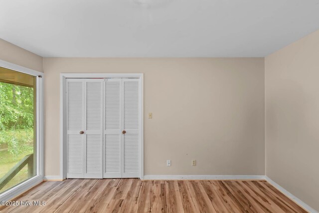 unfurnished bedroom with light wood-style flooring, baseboards, and a closet