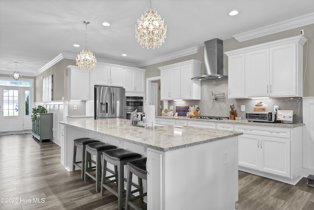 kitchen featuring stainless steel appliances, wall chimney exhaust hood, a chandelier, white cabinets, and recessed lighting