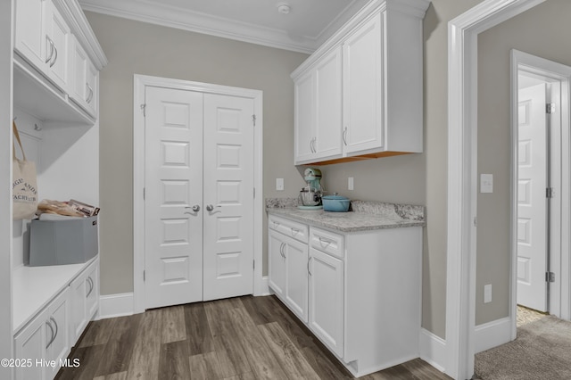 kitchen featuring white cabinets, ornamental molding, dark wood-type flooring, and baseboards