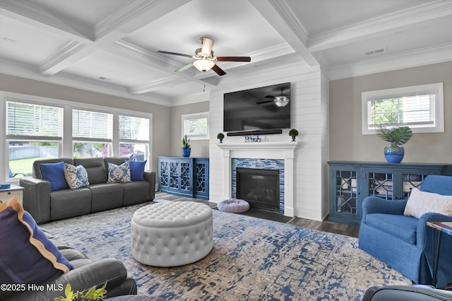 living area featuring coffered ceiling, a ceiling fan, ornamental molding, beamed ceiling, and plenty of natural light