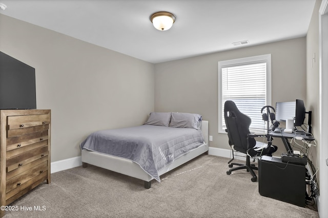 carpeted bedroom with an office area and baseboards