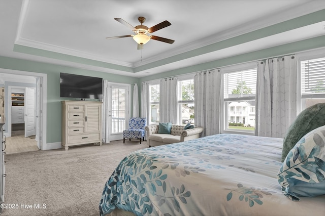 bedroom with a tray ceiling, ornamental molding, carpet, ceiling fan, and baseboards