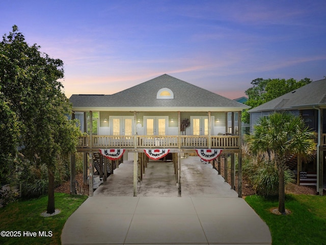 152 NW 1st St, Oak Island, NC 28465 - view of front facade with french doors, concrete driveway, a carport, and roof with shingles