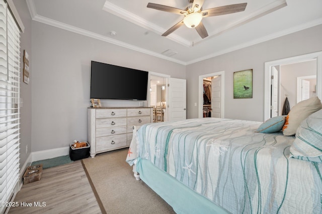 152 NW 1st St, Oak Island, NC 28465 - bedroom featuring a raised ceiling, a spacious closet, crown molding, light wood-style floors, and a closet