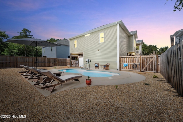 152 NW 1st St, Oak Island, NC 28465 - pool at dusk with a fenced backyard, a gate, and a patio