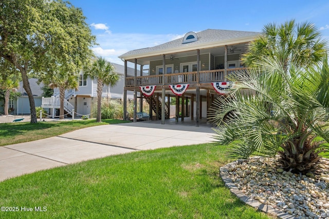 152 NW 1st St, Oak Island, NC 28465 - view of front of home featuring ceiling fan, stairs, concrete driveway, a front lawn, and a carport