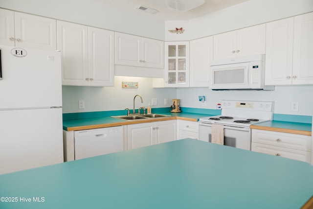 kitchen featuring white appliances, a sink, white cabinetry, and glass insert cabinets