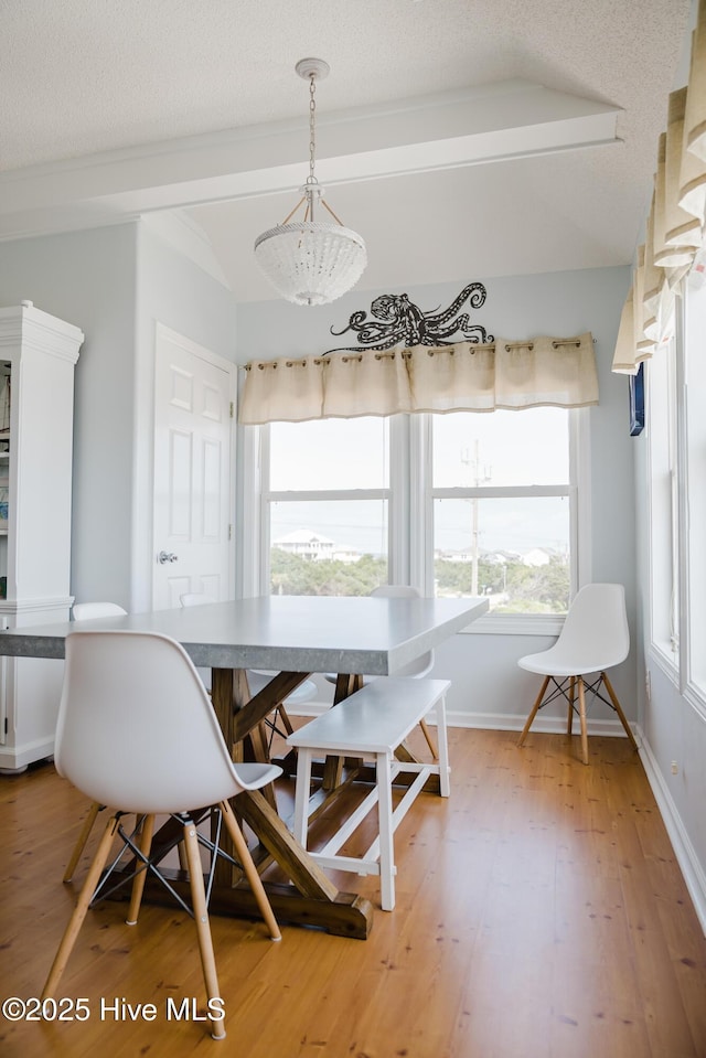 dining area featuring light wood-type flooring, baseboards, a textured ceiling, and lofted ceiling