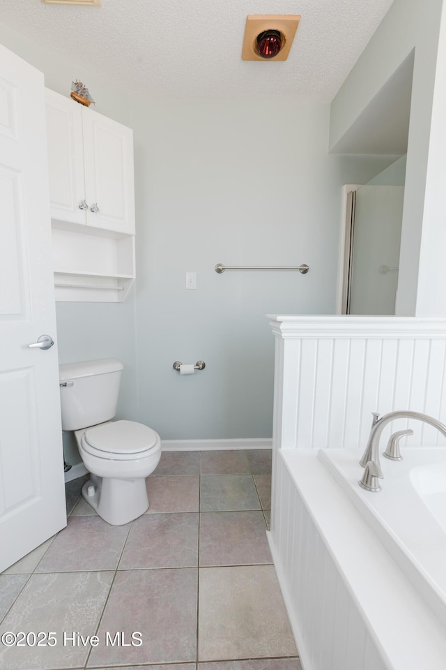 full bathroom featuring toilet, tile patterned floors, and a textured ceiling