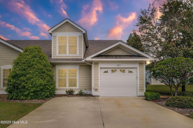 view of front of house with a shingled roof, concrete driveway, and a garage