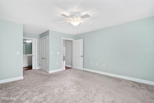 unfurnished bedroom with carpet flooring, baseboards, ensuite bathroom, ceiling fan, and a closet