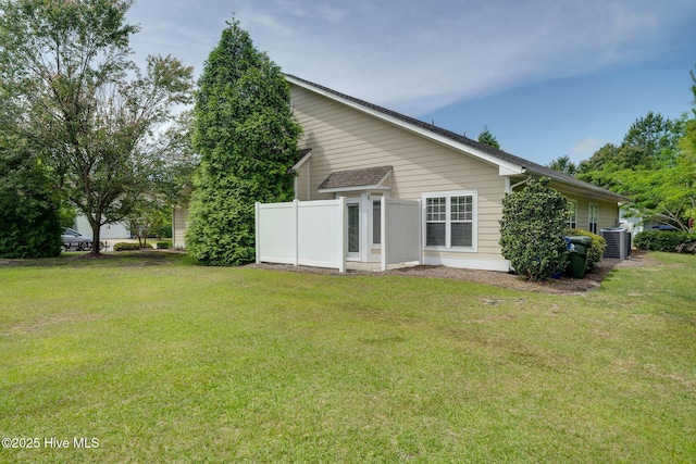 back of house with central AC unit and a yard
