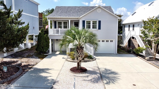 coastal inspired home featuring stairway, concrete driveway, an attached garage, and a shingled roof